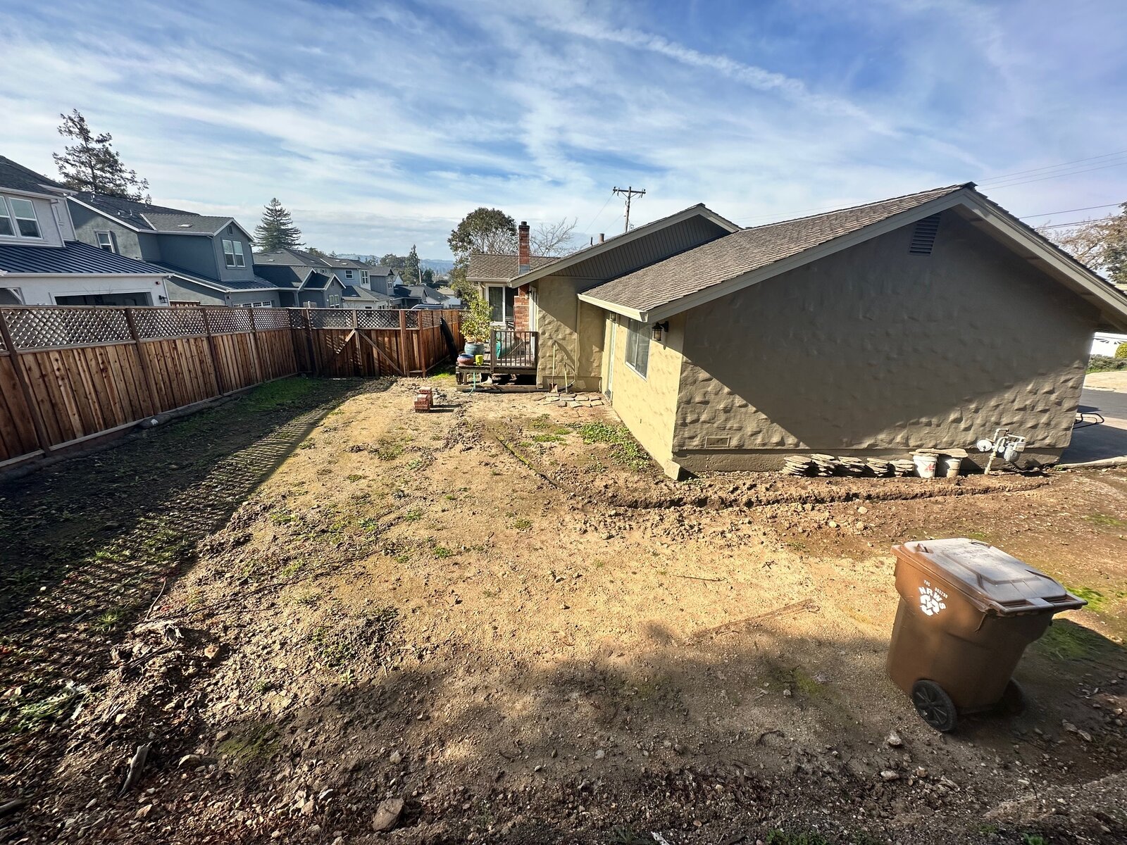 Main patio before — bare hillside with dirt and old deck