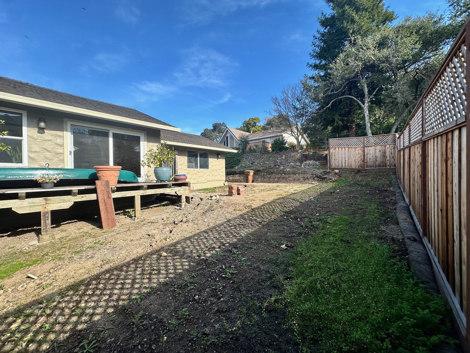Backyard before — old raised deck with bare dirt yard and no landscaping