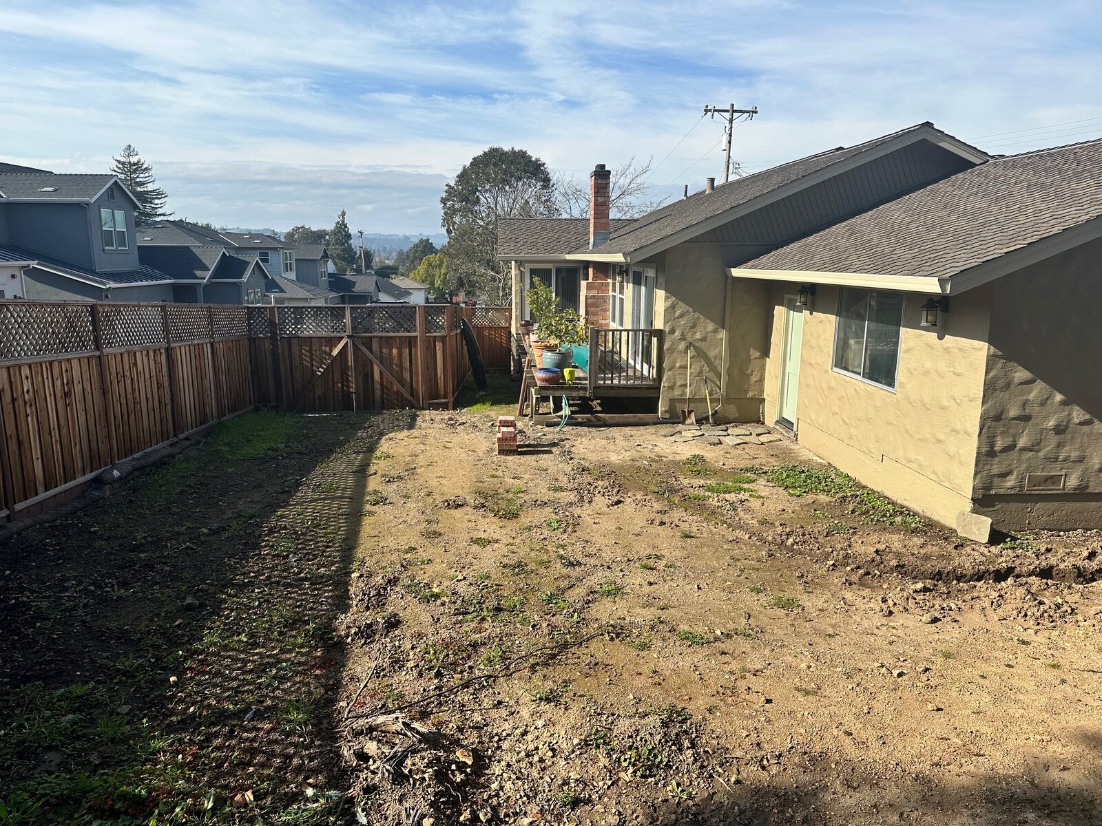 Backyard aerial before — bare hillside with old deck and dirt yard